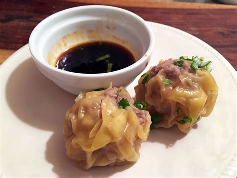 Two Dumplings On A Plate With Dipping Sauce