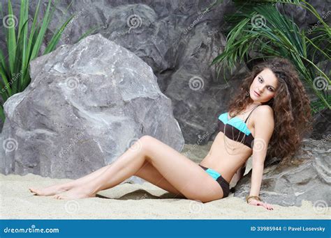 La Mujer Hermosa Joven En Bikini Se Sienta En La Arena Foto De Archivo