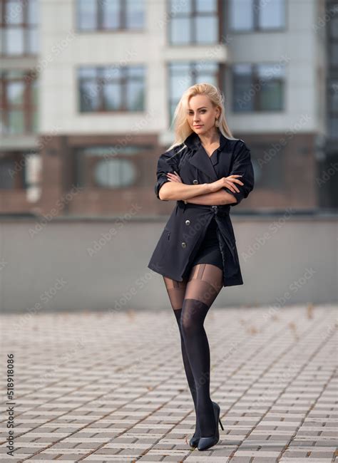 Beautiful Blonde Girl In A Black Coat With Perfect Legs In Black Pantyhose And Shoes With High