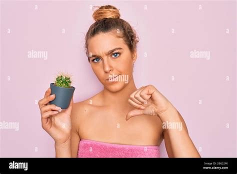 Schöne blonde Frau mit blauen Augen tragen Handtuch Dusche nach Bad mit kleinen Kaktus mit