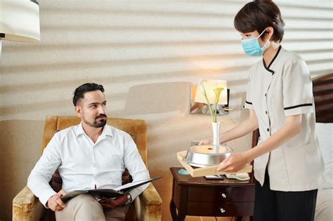 Premium Photo Smiling Handsome Mature Man Looking At Maid In Medical Mask Bringing Fresh