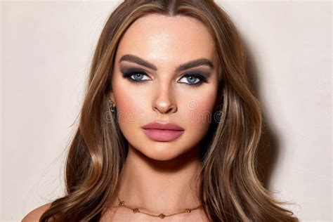 Caucasian Portrait Of A Beautiful Blonde Haired Female With Soft Make Up Against A White Wall