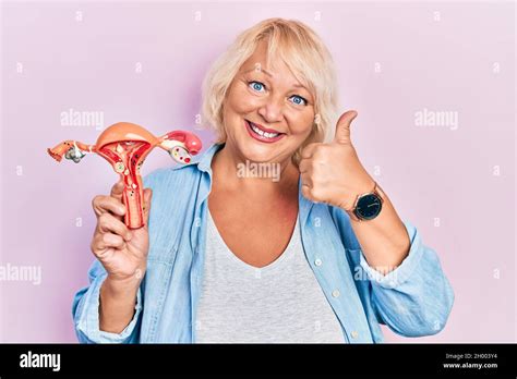 Middle Age Blonde Woman Holding Anatomical Model Of Female Genital Organ Smiling Happy And