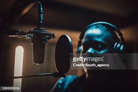 Black Female Singer Singing Into Microphone In Recording Studio High