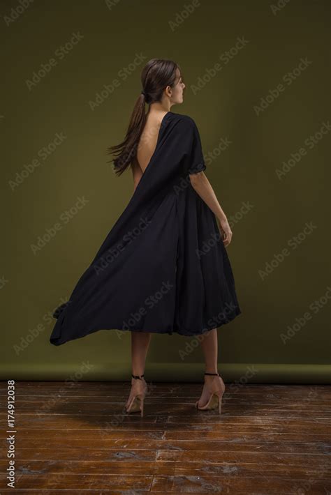 Beautiful Naked Woman With Perfect Body In Black Dress Posing Isolated On The Green Background