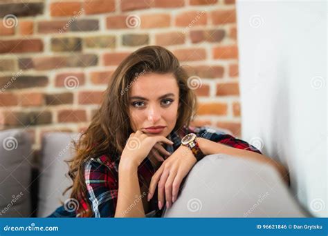 Smiling Beautiful Brunette Relaxing On The Couch And Looking At Camera In The Living Room Stock