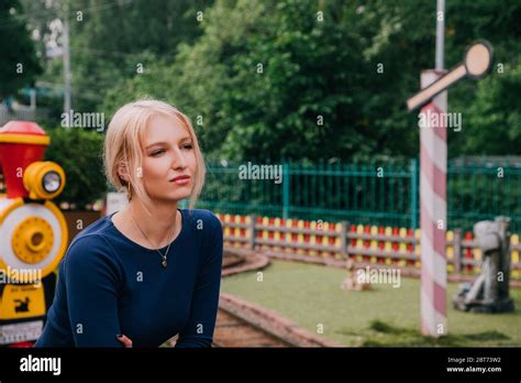 H Bsche Blonde Frau In Straff Blauem Kleid Vor Einer Attraktion Mit Einem Zug Auf Einem Kirmes
