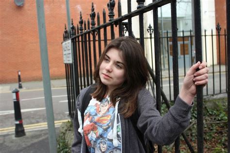 A Woman Standing Next To A Black Fence