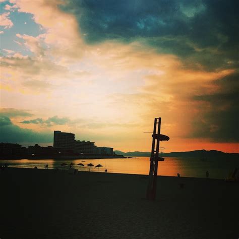 Polo de silhueta na praia contra o céu nublado durante o pôr do sol