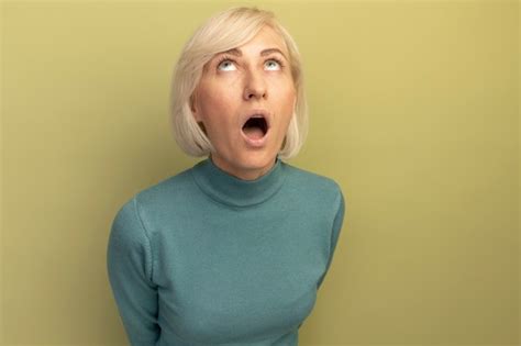 Überraschte hübsche blonde slawische frau schaut isoliert auf olivgrüner wand auf Kostenlose Foto