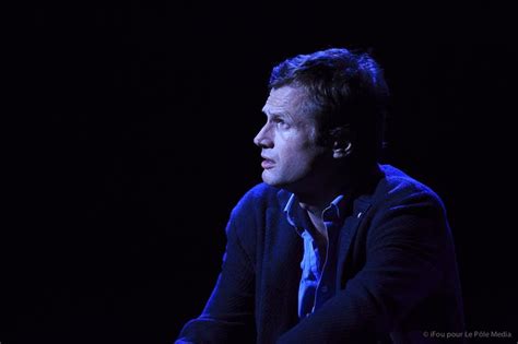 A Man Sitting In Front Of A Black Background With His Hands On His