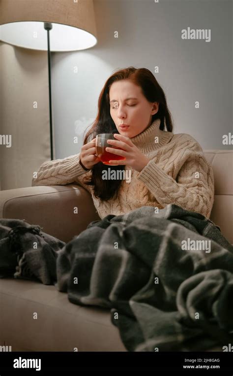 Woman At Home Is Treated With Hot Tea While Sitting On A Beige Sofa Stock Photo Alamy
