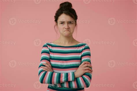 Portrait Of Attractive Disappointed Looking Girl With Brunette Hair And Bun Wearing Striped
