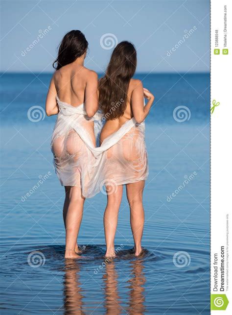Duas Mulheres Novas Do Nude Envolvidas No Xaile Branco Que Levanta Na Praia Foto De Stock