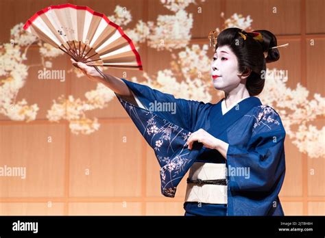 A Japanese Geisha Wearing A Kimono Performs A Traditional Fan Dance At