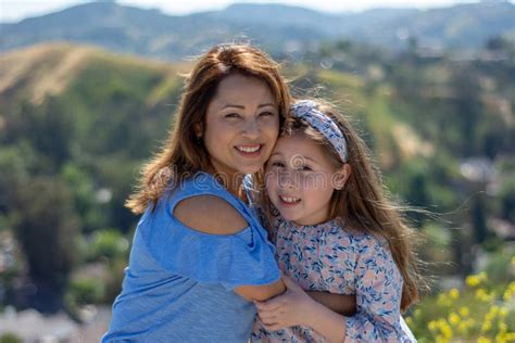 Madre E Hija De Latina Que Sonr En Y Que R En En Una Colina Delante De Las Flores Amarillas Foto