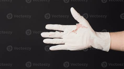 Hand Wearing torn latex glove or torn rubber gloves on black background