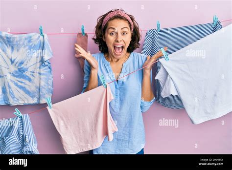 Jeune femme brunette faisant la lessive autour de la ficelle pend célébrant fou et stupéfait