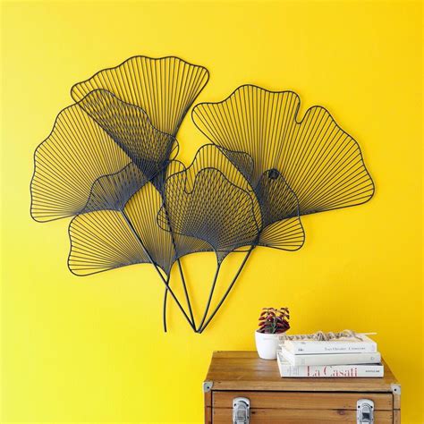 Three Metal Fan Shaped Sculptures On A Yellow Wall