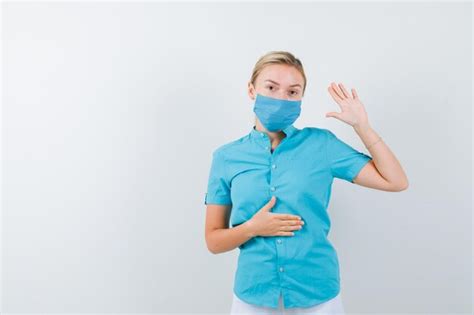 Jeune Femme Blonde Agitant La Main Pour Saluer Tout En Gardant La Main Sur Le Ventre Photo