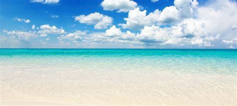 Clear Blue Water And White Clouds On An Empty Beach