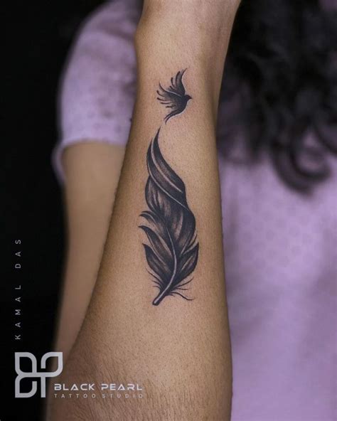 A Woman S Arm With A Black Feather Tattoo On It