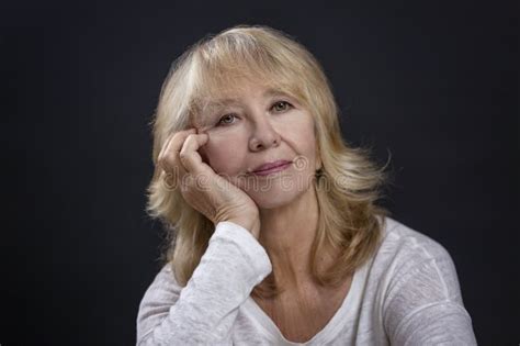 Portrait Of A Beautiful Elderly Woman A Smiling Blonde Sits With Her Hand Resting Her Cheek