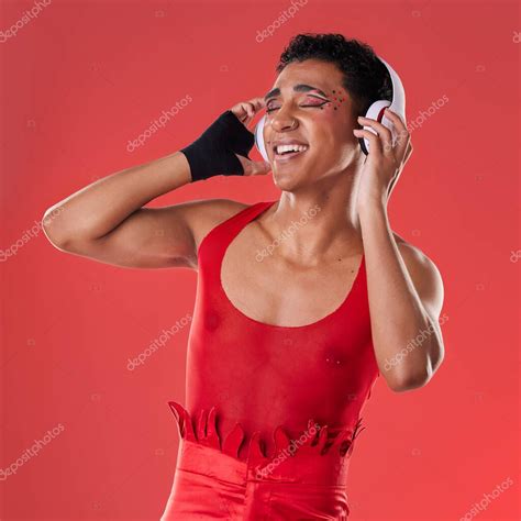 Baile música y hombre gay con auriculares aislados sobre un fondo rojo en un estudio Libertad