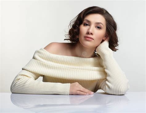 Beautiful Brunette Woman Dressed In Large White Woolen Sweater Is Sitting At White Table Stock