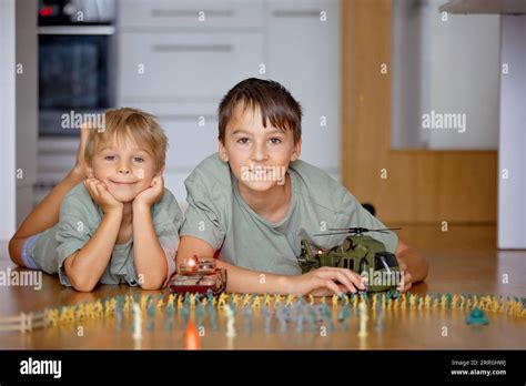 Happy Children Siblings Boy Playing With Tanks And Soldiers At Home