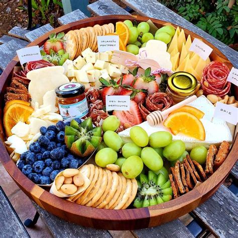 A Wooden Platter Filled With Cheese Fruit And Crackers