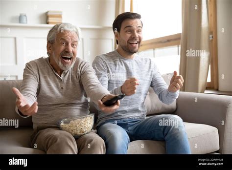 Overjoyed Mature Father With Son Watching Tv Having Fun Together Stock Photo Alamy