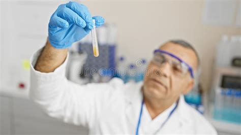 Mature Hispanic Man In Lab Coat Examining Test Tube In A Laboratory