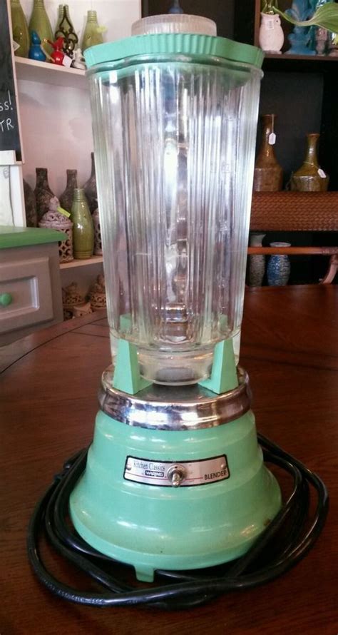 A Green Blender Sitting On Top Of A Wooden Table Next To A Black Cord