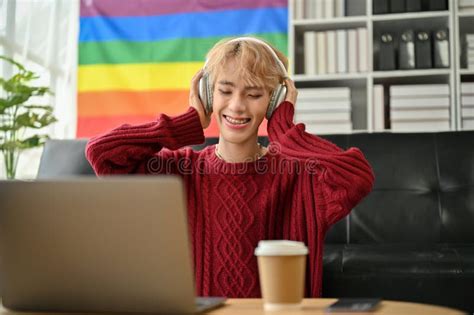 A Happy Asian Gay Man Is Listening To Music Through His Headphones In The Living Room Stock