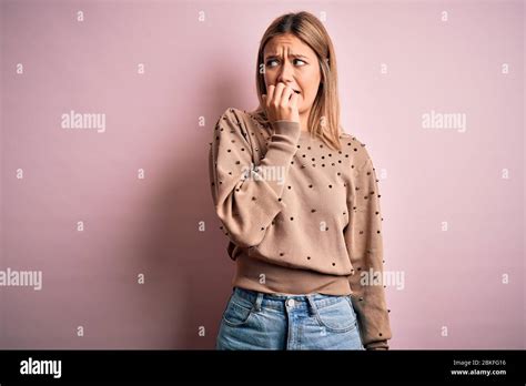 Jeune femme blonde portant un pull de mode sur fond rose isolé regardant stressé et nerveux avec