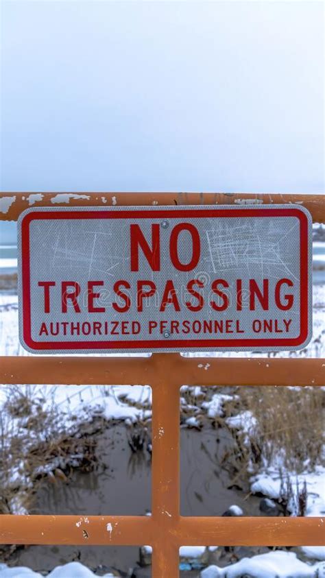 Vertical No Trespassing Sign on an Old Metal Fence Against Distant Lake and Cloudy Sky Stock ...