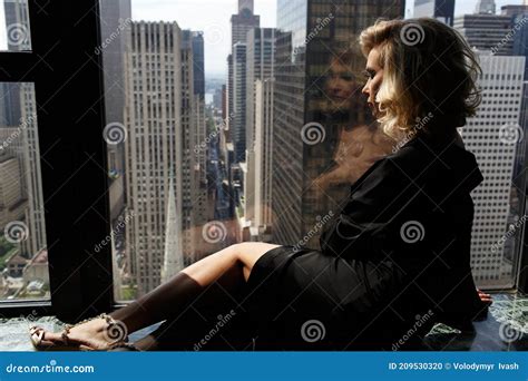 Woman In Black Silk Robe Lies With Naked Shoulders Before A Panoramic Window In New York Stock