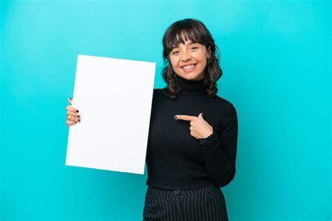 Jovem mulher latina isolada em fundo azul segurando um cartaz vazio expressão feliz e