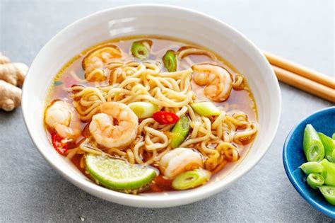 Азиатская лапша с креветками и овощами подается в миске на темном фоне ...