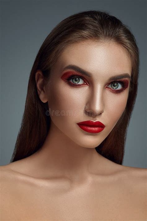 Close Up Glamour Portrait Of A Beautiful Half Naked Model With Bright Make Up Posing Over A Gray