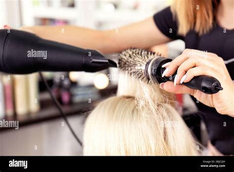 Hairdresser drying blonde's hair at salon Stock Photo - Alamy