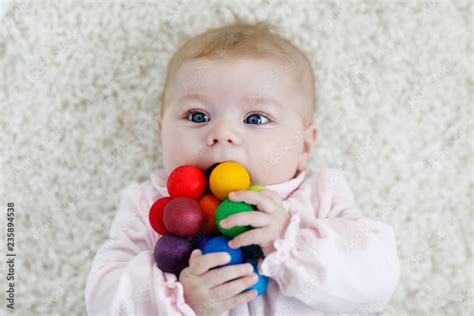 Cute Adorable Newborn Baby Playing With Colorful Wooden Rattle Toy Ball
