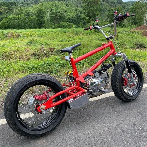 A Red And Black Bike Parked On The Side Of A Road Next To Some Grass