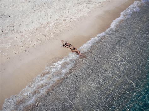 Chica delgada en bikini está tomando el sol en la playa de arena en la isla de phuket en