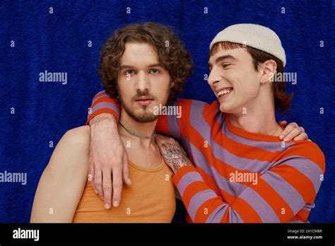 Two Joyful Good Looking Gay Men In Vibrant Clothes Posing On Dark Blue Backdrop Pride Month