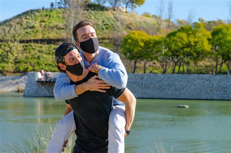 Happy Tender Gay Couple Boyfriends With Protective Face Mask Together Playing Up On Back And