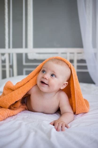 Premium Photo Naked Baby Boy Lies Under An Orange Towel On The Bed