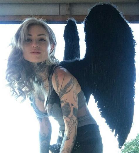 A Woman With Large Black Wings On Her Chest Posing For A Photo In Front