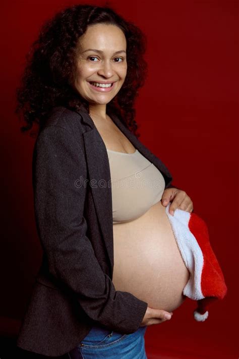 Charming Pregnant Pretty Woman Holding Santa Hat Over Her Naked Big